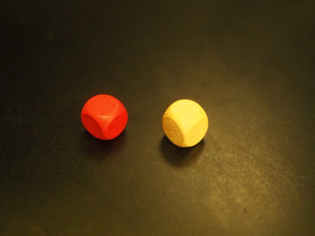 Two blank wood dice—one painted red, one plain