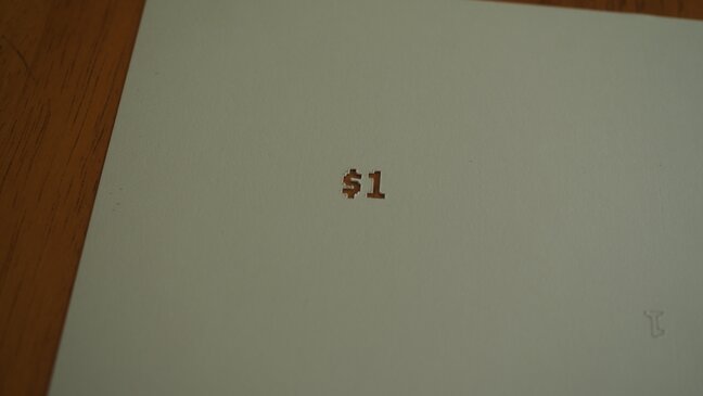 A $1 hole cut in cardstock